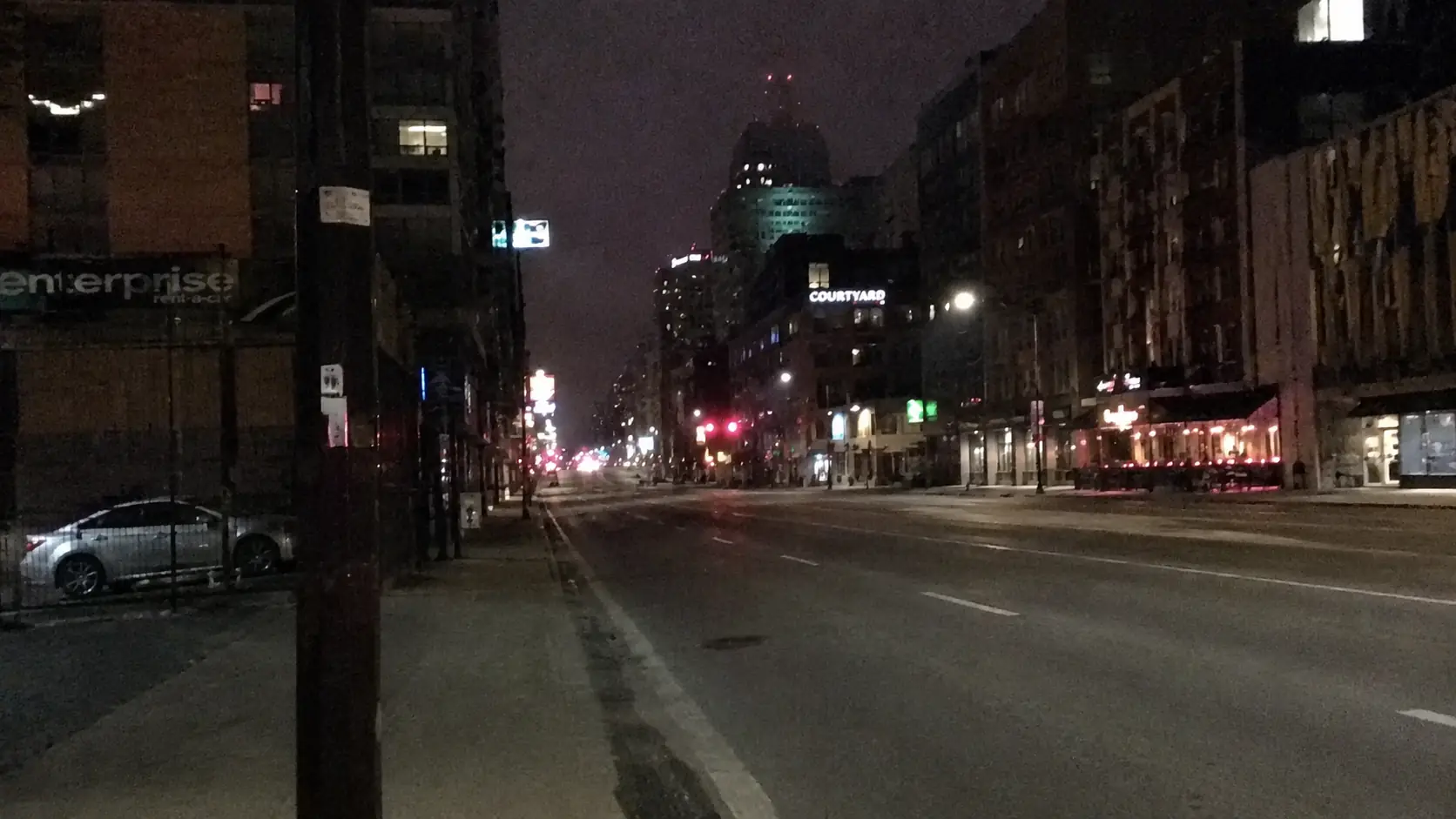 Before-and-after slider for a noisy low-light city street cleaned for better contrast and detail.