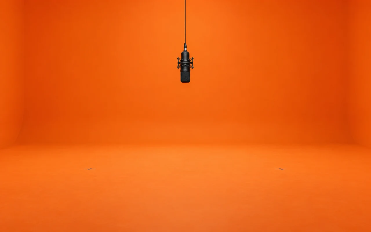 Empty seamless orange studio with one hanging microphone in the center
